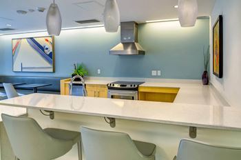 Community kitchen with a long counter and chairs and efficient appliances at The Parker Apartments, Oregon, 97209